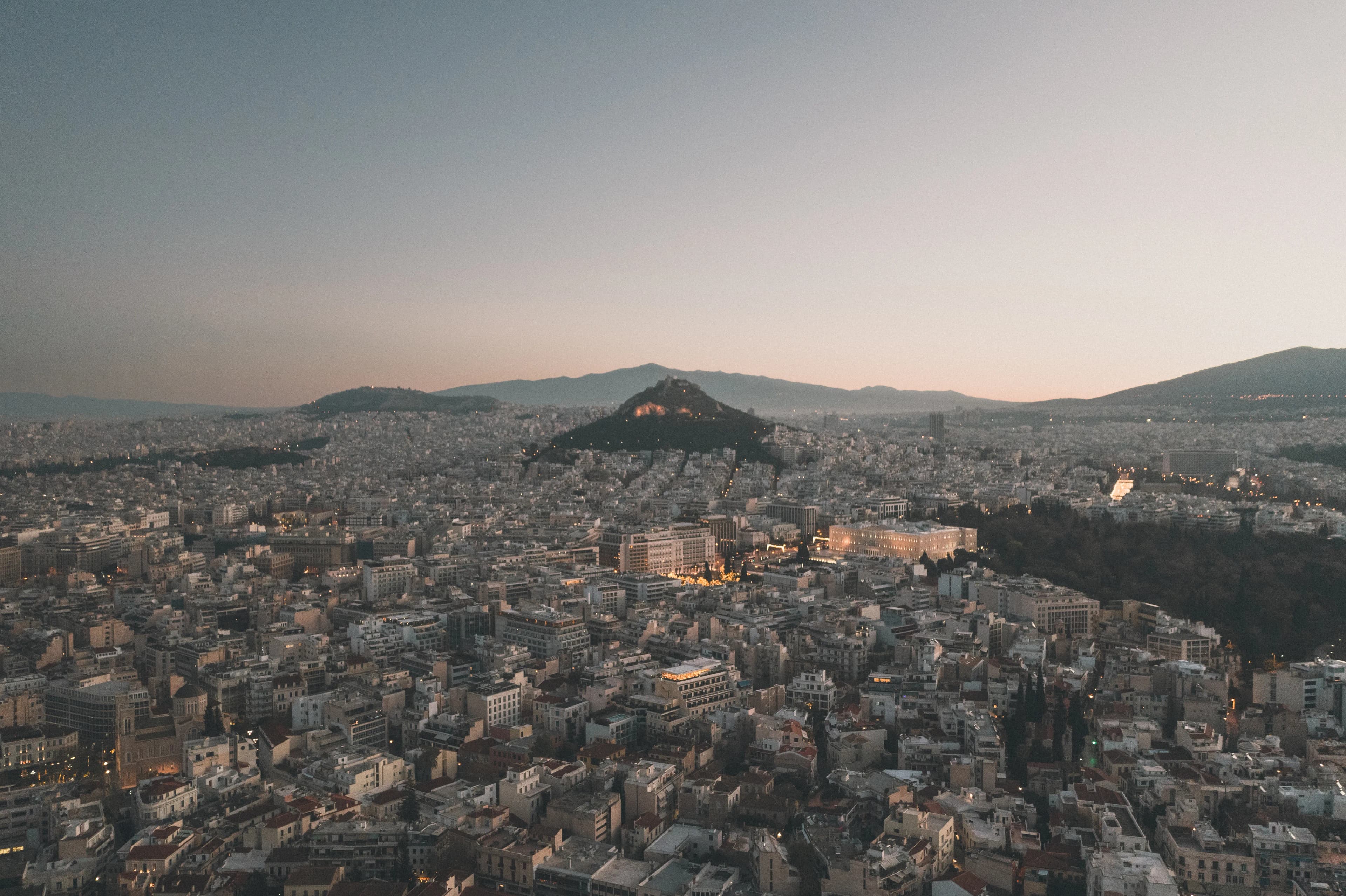 Athens at dusk seen from above, with Lycabettus Hill in the distance